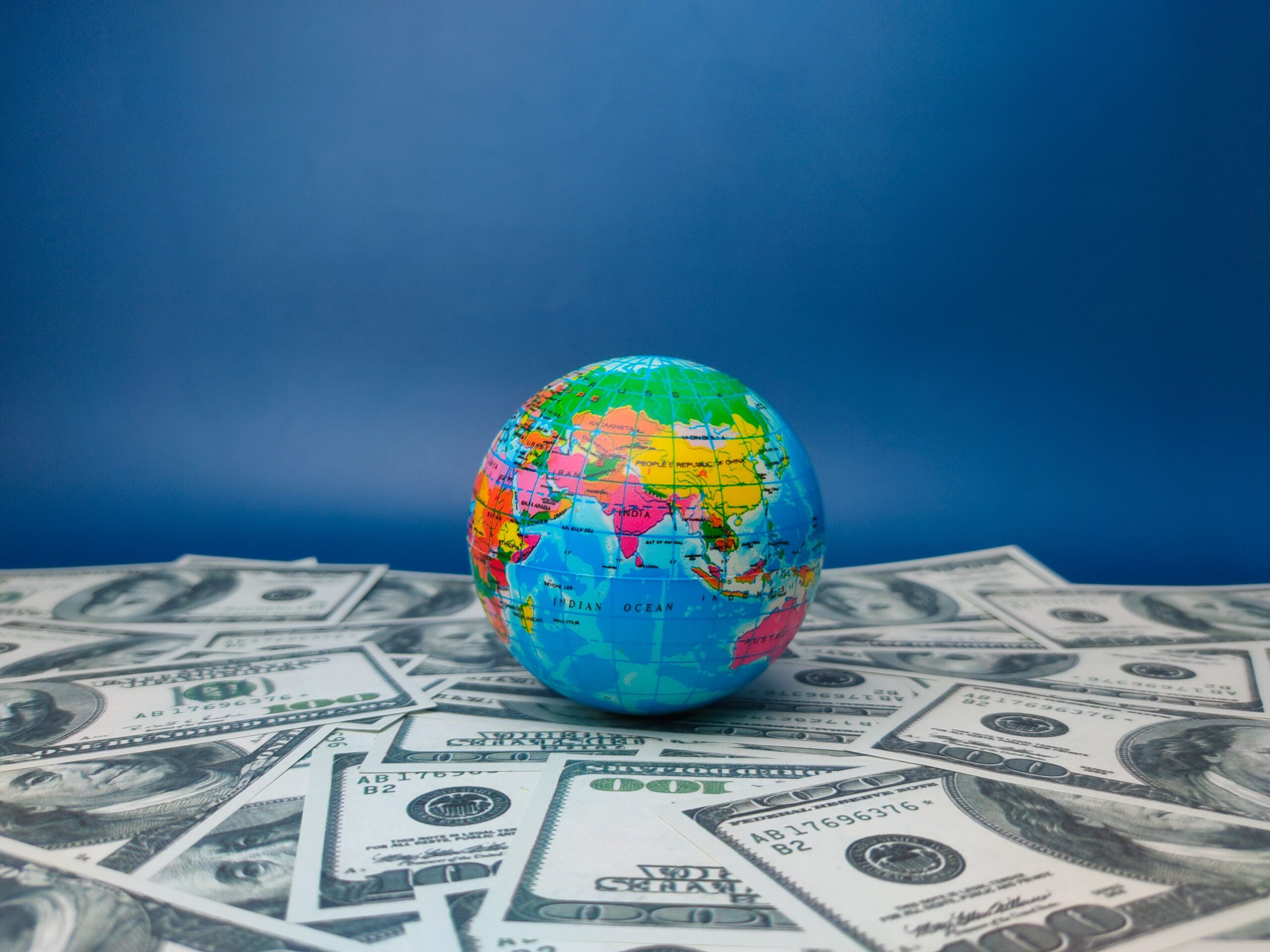 A world globe with a stack of money in the foreground, demonstrating global commerce and financial success
